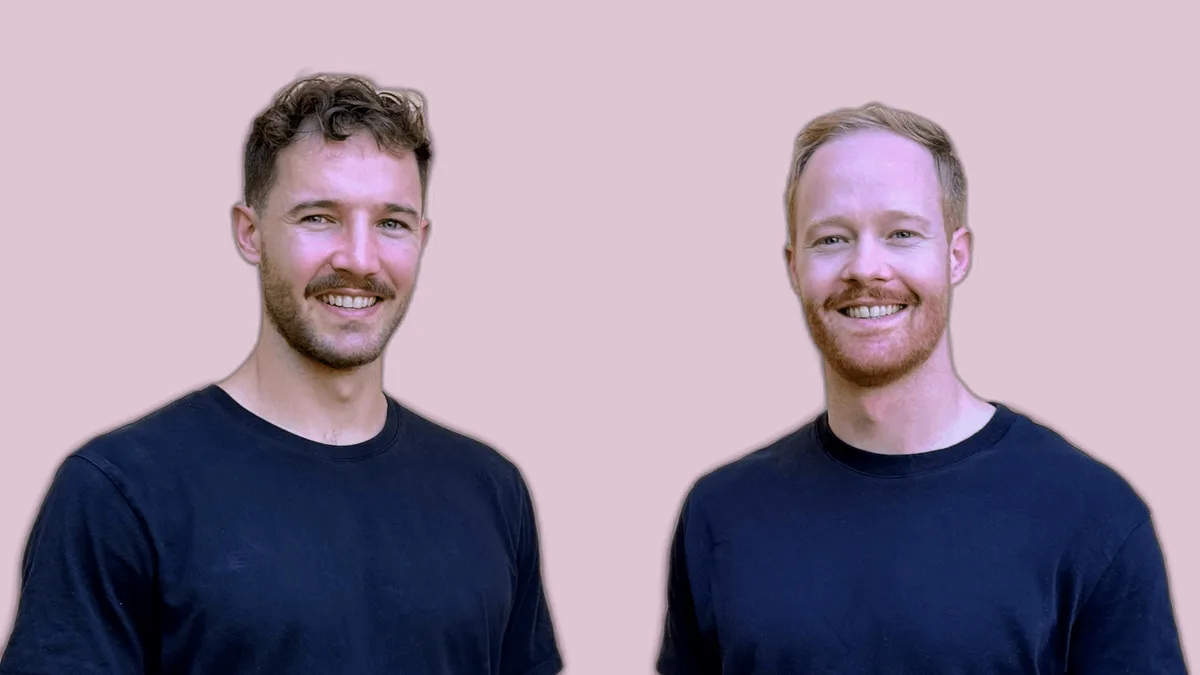 Julian and Marius Koechlin, standing side by side against a plastered wall
